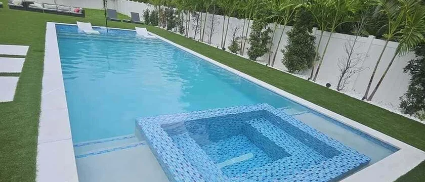 Custom pool with sunken spa, stepping pads and large-format deck tile at dusk