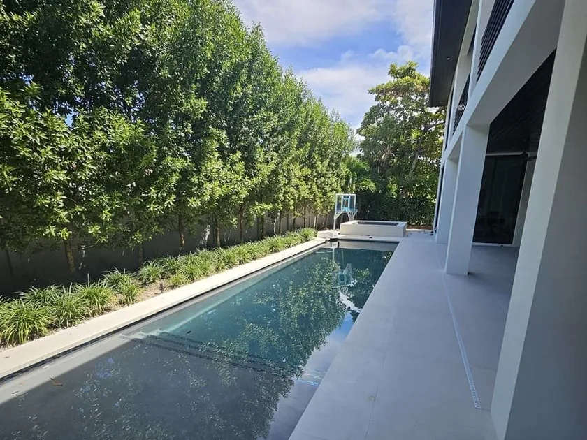 Dark-finish lap pool running alongside a modern white house